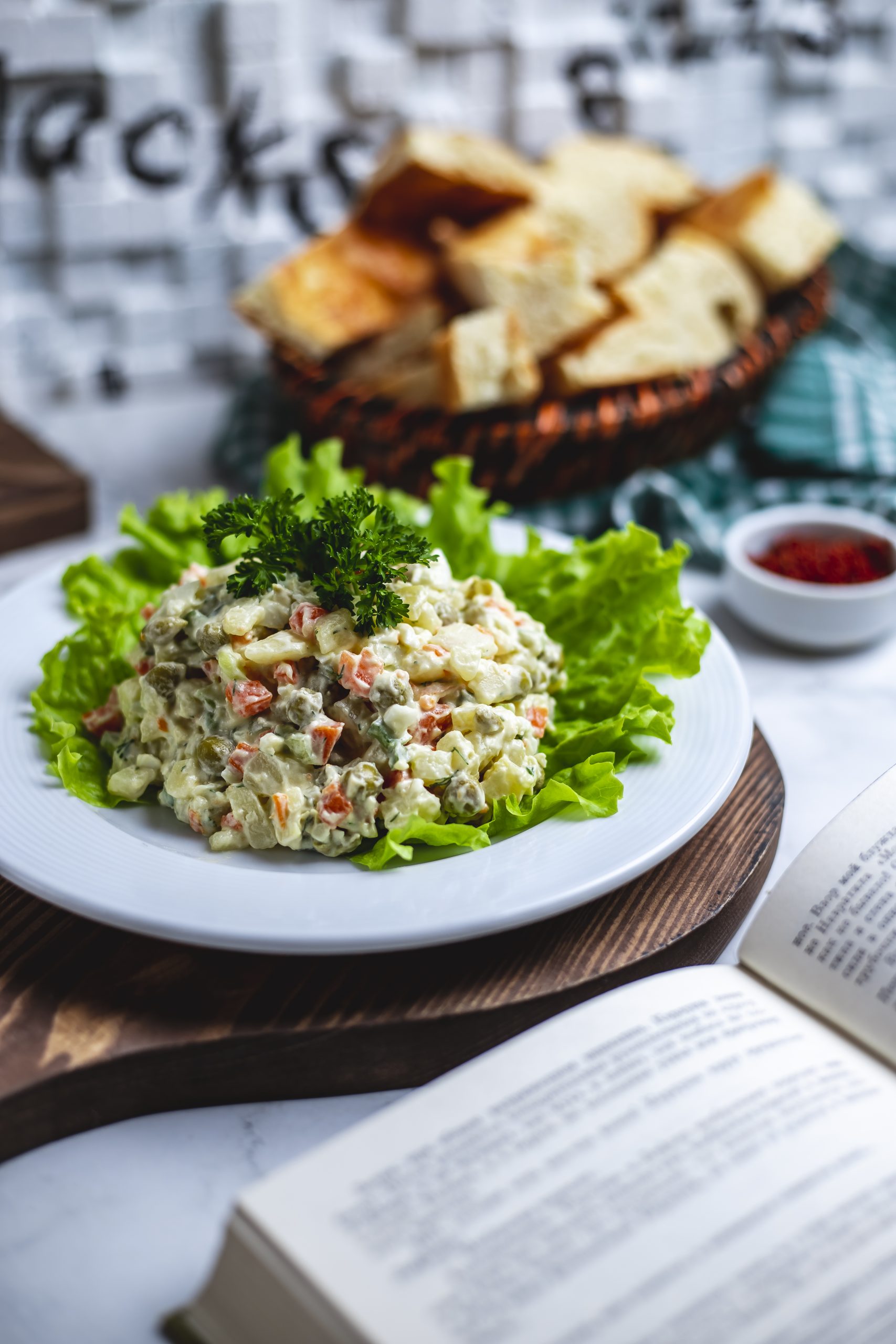 side view capital salad on lettuce with a basket of bread